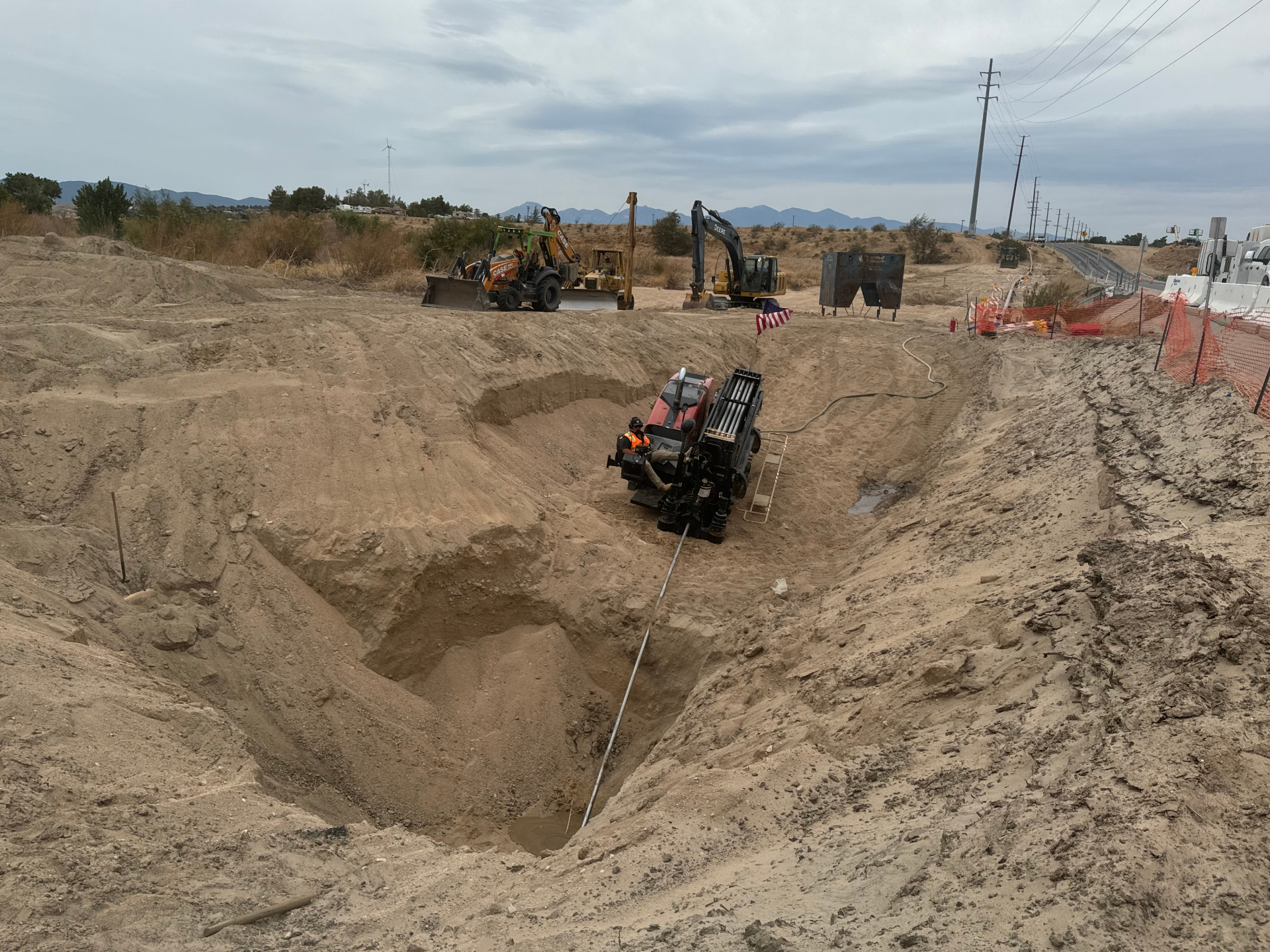 Wide shot of the bore pit with rig, flag, and support fleet on the shoulder